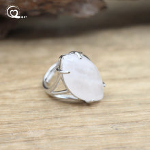 Silver ring with a large white stone on a wooden surface