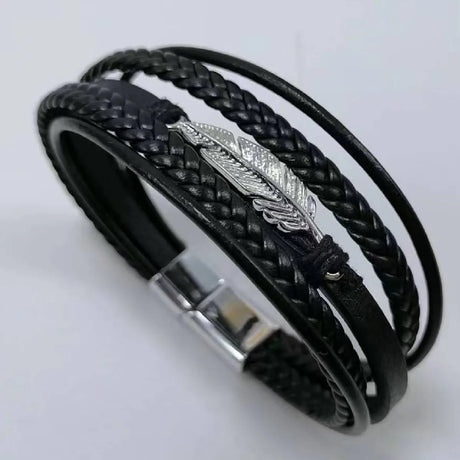 Black braided leather bracelet with silver feather charm on a light gray background