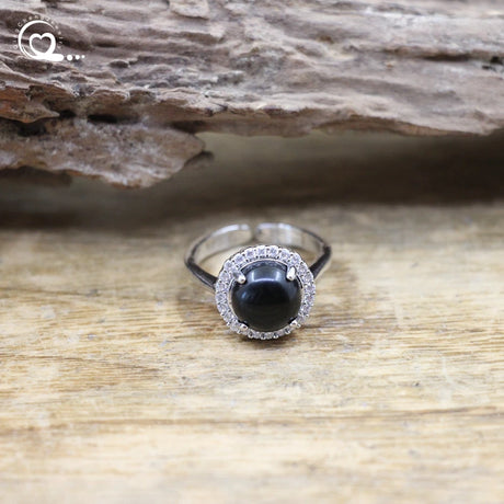 Ring with a black gemstone and silver halo on a wooden surface