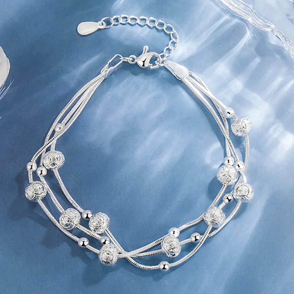 Silver bracelet with beads on a blue textured background