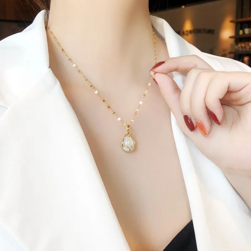 Gold necklace with a teardrop-shaped pendant worn by a person.