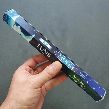 Hand holding a LUNE and MOON product packaging against a gray background