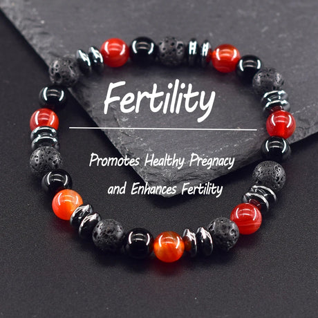 Beaded bracelet with red and black stones on a dark surface, labeled 'Fertility'.