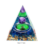 Pyramid-shaped crystal with purple and green balls inside on a white background