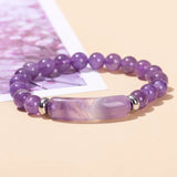 Purple beaded bracelet with silver accents on a light pink background