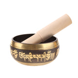 Tibetan singing bowl with gold script and wooden striker on a white background