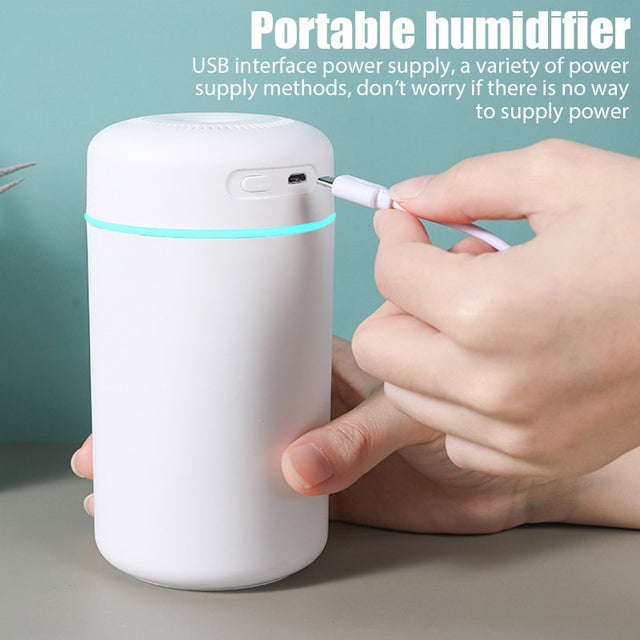Portable humidifier with USB interface being charged by a hand on a neutral background