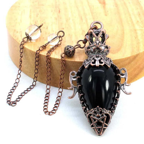 Decorative black pendant with intricate metalwork on a wooden surface
