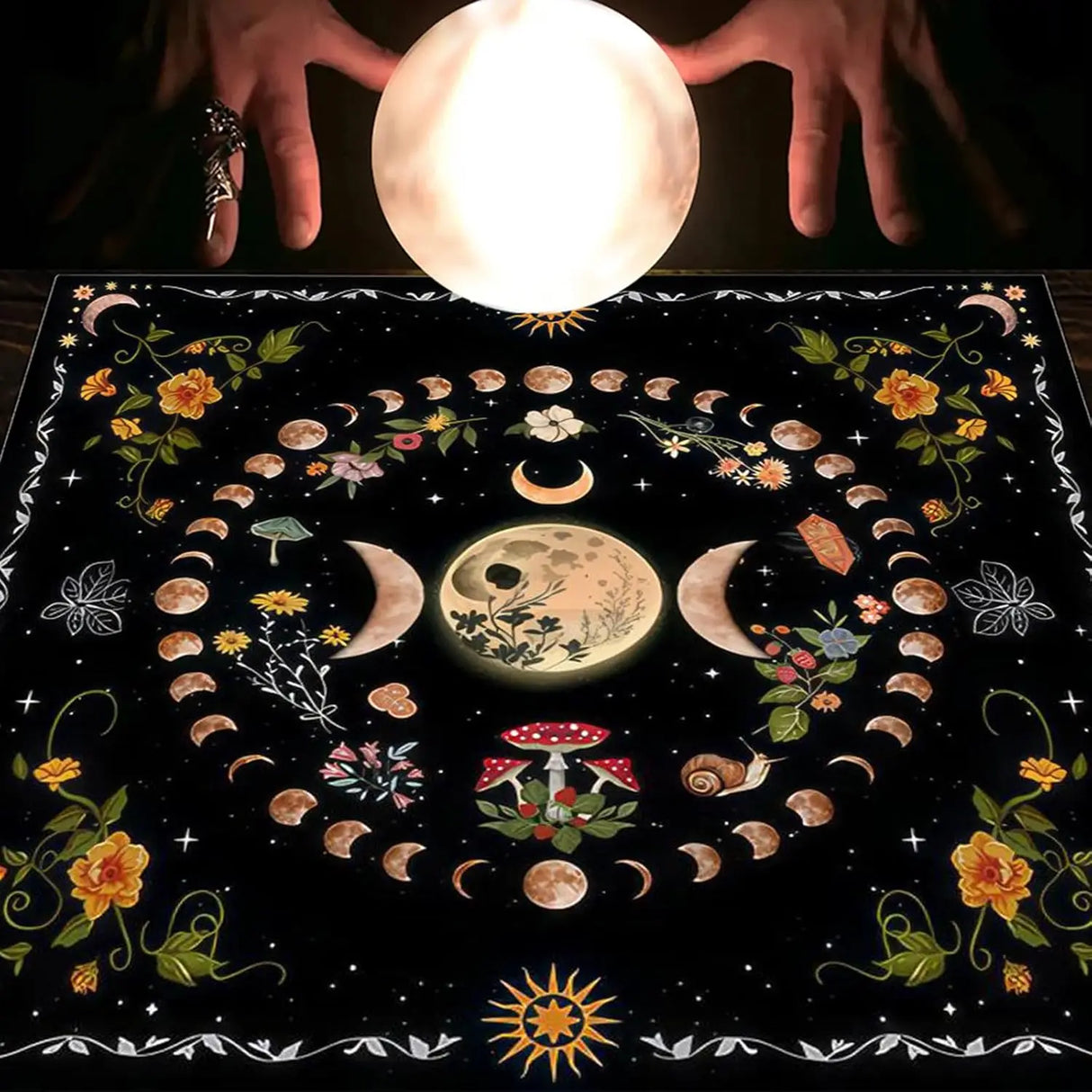 Decorative cloth with moon phases and floral patterns, held by hands above a glowing orb.