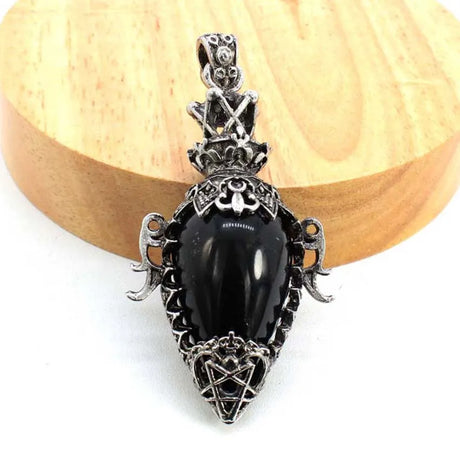 Black pendant with silver decorative elements on a wooden surface