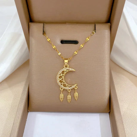 Gold necklace with a crescent moon pendant in an open beige jewelry box.