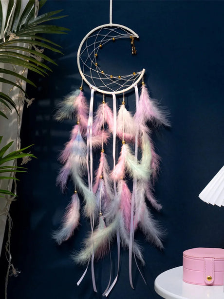 Decorative dreamcatcher with pastel feathers against a dark blue wall.