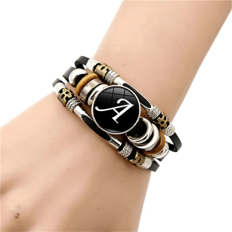 Multistrand bracelet with a central black disc featuring a white letter 'A' on a wrist.