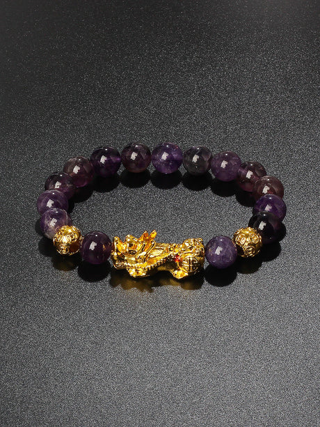 Amethyst beaded bracelet with a gold charm on a dark background
