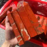 Red marbled objects held by a hand with a red basket in the background
