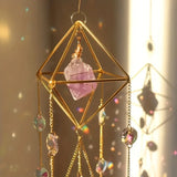 Decorative hanging crystal with gold frame and pink crystal on a blurred background