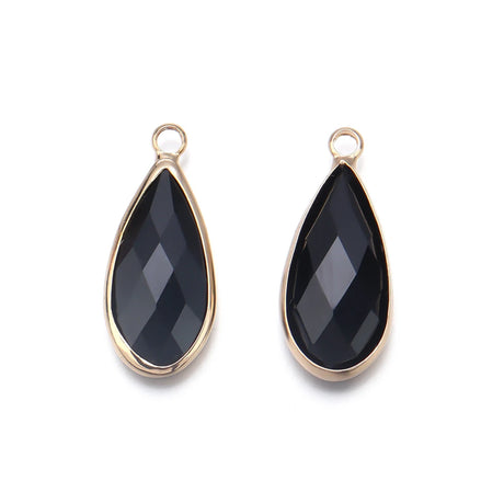 Teardrop-shaped black stones with gold frames on a white background