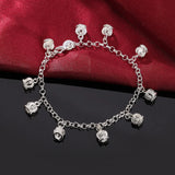 Silver bracelet with charms on a red fabric background