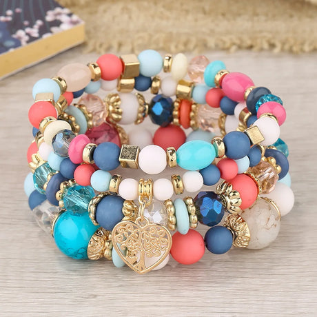 Colorful beaded bracelets with a heart charm on a wooden surface