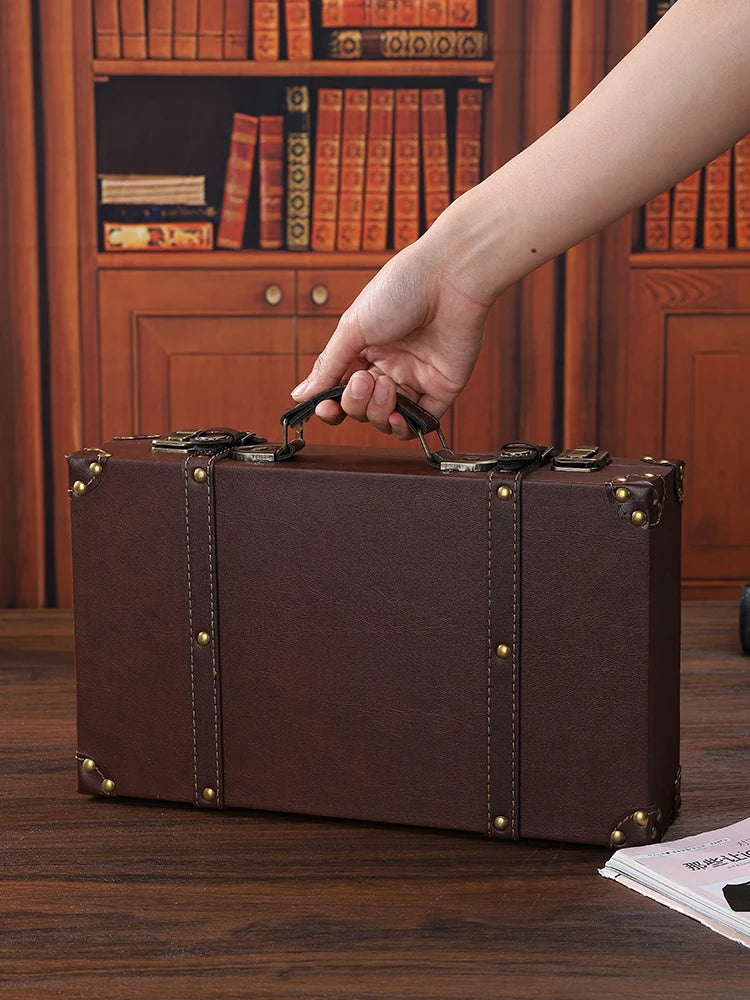 Brown leather suitcase being held by a hand in front of a bookshelf.