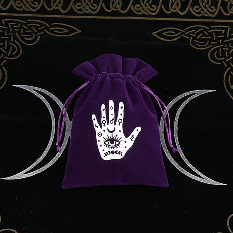Purple drawstring bag with a white hand design featuring an eye on a black background with moon symbols.