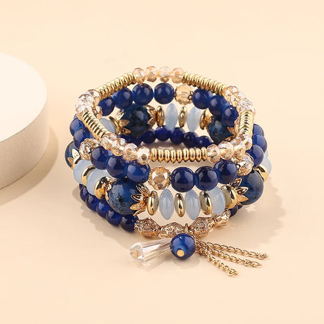 Stack of blue beaded bracelets with gold accents on a beige background