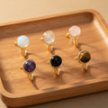 Set of six gold rings with different gemstones on a white background
