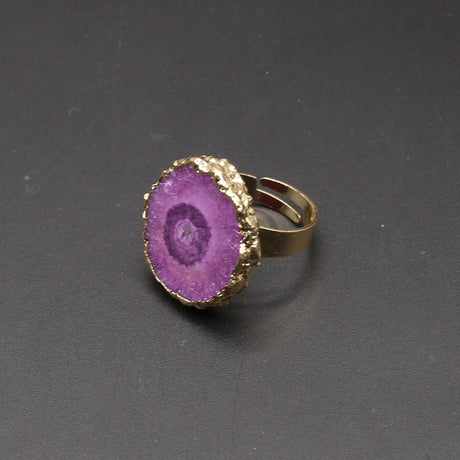Ring with purple gemstone and gold band on a dark gray background