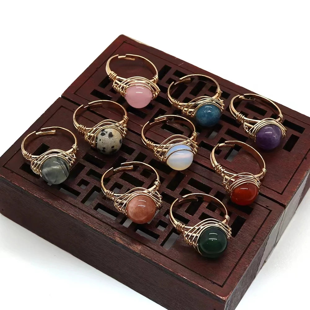 Set of gold-wire-wrapped stone rings on a wooden display box