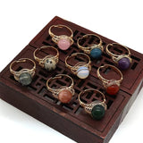 Set of gold-wire-wrapped stone rings on a wooden display box