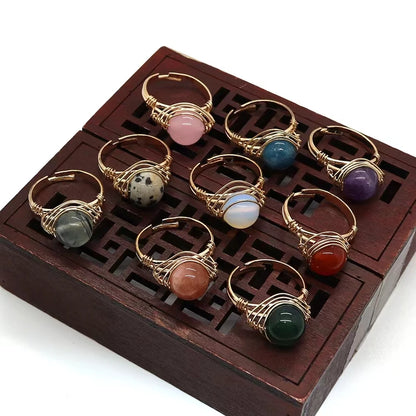 Set of gold-wire-wrapped stone rings on a wooden display box