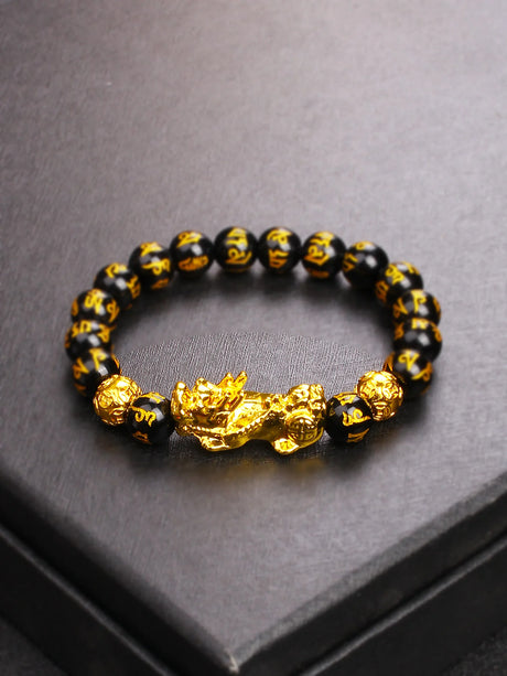 Black beaded bracelet with gold dragon design on a gray surface