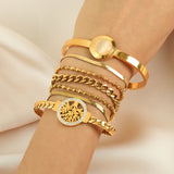 Gold bracelets on a wrist against a beige background