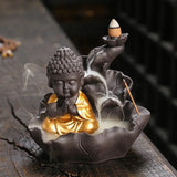 Buddha-shaped incense burner with incense sticks on a dark surface