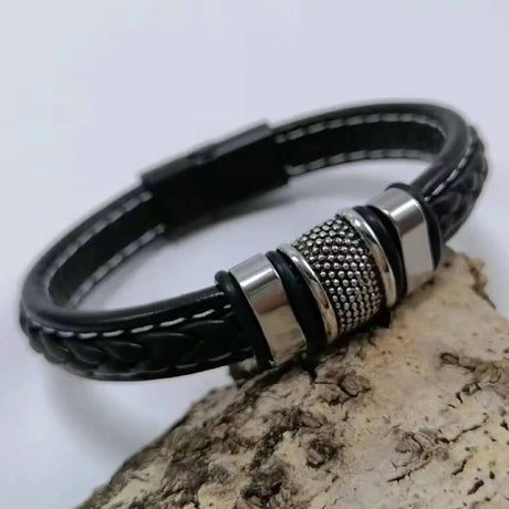 Black leather bracelet with silver clasp on a wooden surface