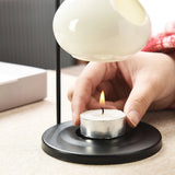 Person lighting a tealight candle using a lamp