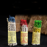 Three bundles of incense with colorful tops and labels on a dark background