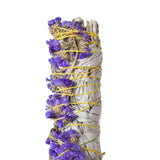 White sage smudge stick with purple flowers and yellow string on a white background