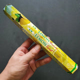 Hand holding a box of Lemon Twist incense sticks against a dark background