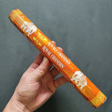 Hand holding a box of Royal Chandan incense sticks against a dark background