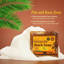 African Black Soap with Organic Shea Butter bar with rich lather and palm leaf on brown background.