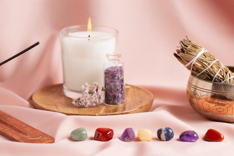 Candle, crystals, and incense on a pink fabric background