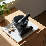 Black soapstone mortar and pestle set for crushing whole spices, herbs, and garlic during food preparation.