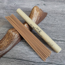 Unopened package of brown incense with a wooden holder on a gray wooden surface