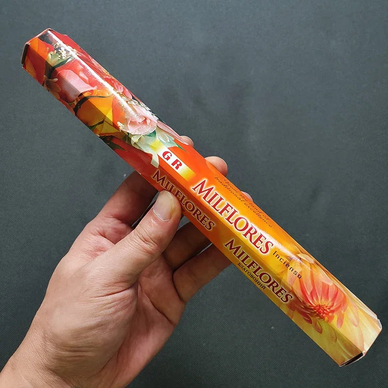 Hand holding a colorful package of Milflores against a dark background