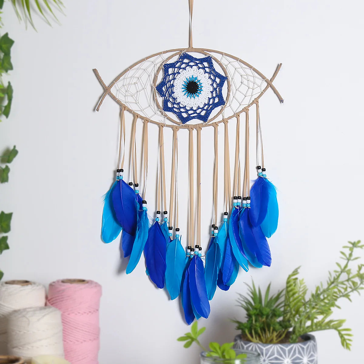 Evil Eye dream catcher with blue feathers hanging ornament for bedroom decor, peaceful ambiance, and protective wall display.