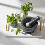 Gray and black soapstone mortar and pestle bowl set for crushing garlic, peppercorns, and fresh herbs for cooking.