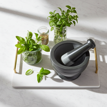 Gray and black soapstone mortar and pestle bowl set for crushing garlic, peppercorns, and fresh herbs for cooking.