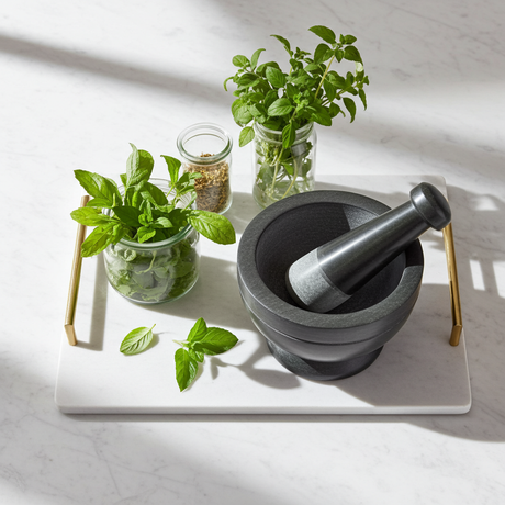 Gray and black soapstone mortar and pestle bowl set for crushing garlic, peppercorns, and fresh herbs for cooking.