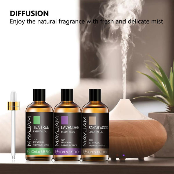 MAYJAM tea tree, lavender and sandalwood 100ml essential oil bottles beside a wood-base ultrasonic diffuser in use